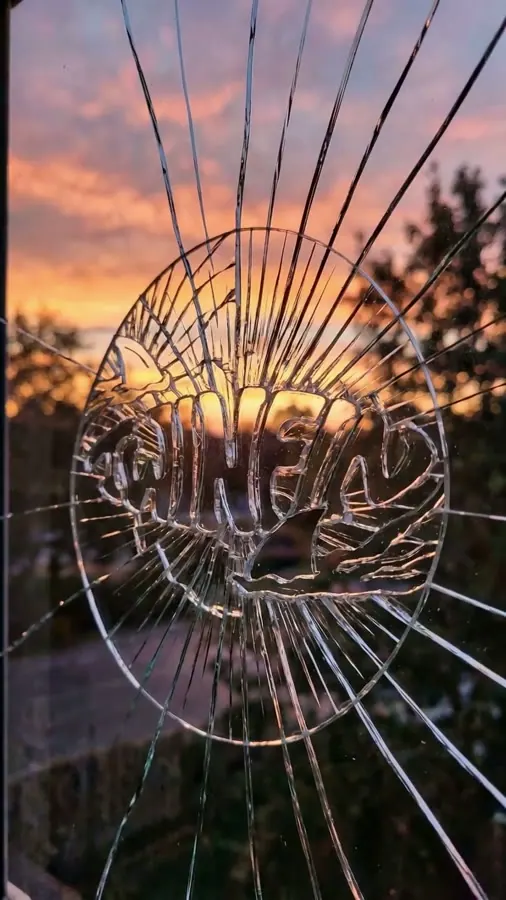 El logo de TWINFIN grabado en un cristal hecho añicos, con una puesta de sol detrás